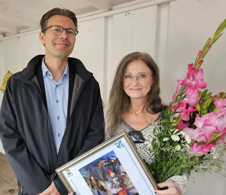 En man och en kvinna tar emot ett pris och blommor.